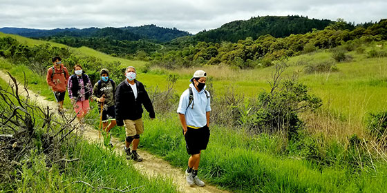 family hiking wearing face masks for safe social distancing